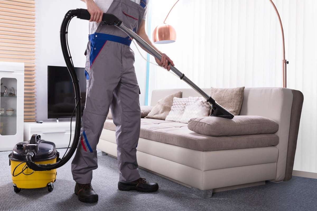 Entreprise de nettoyage : Un technicien nettoie soigneusement un canapé avec un appareil spécialisé, démontrant le professionnalisme et la précision de l'entreprise de nettoyage.
